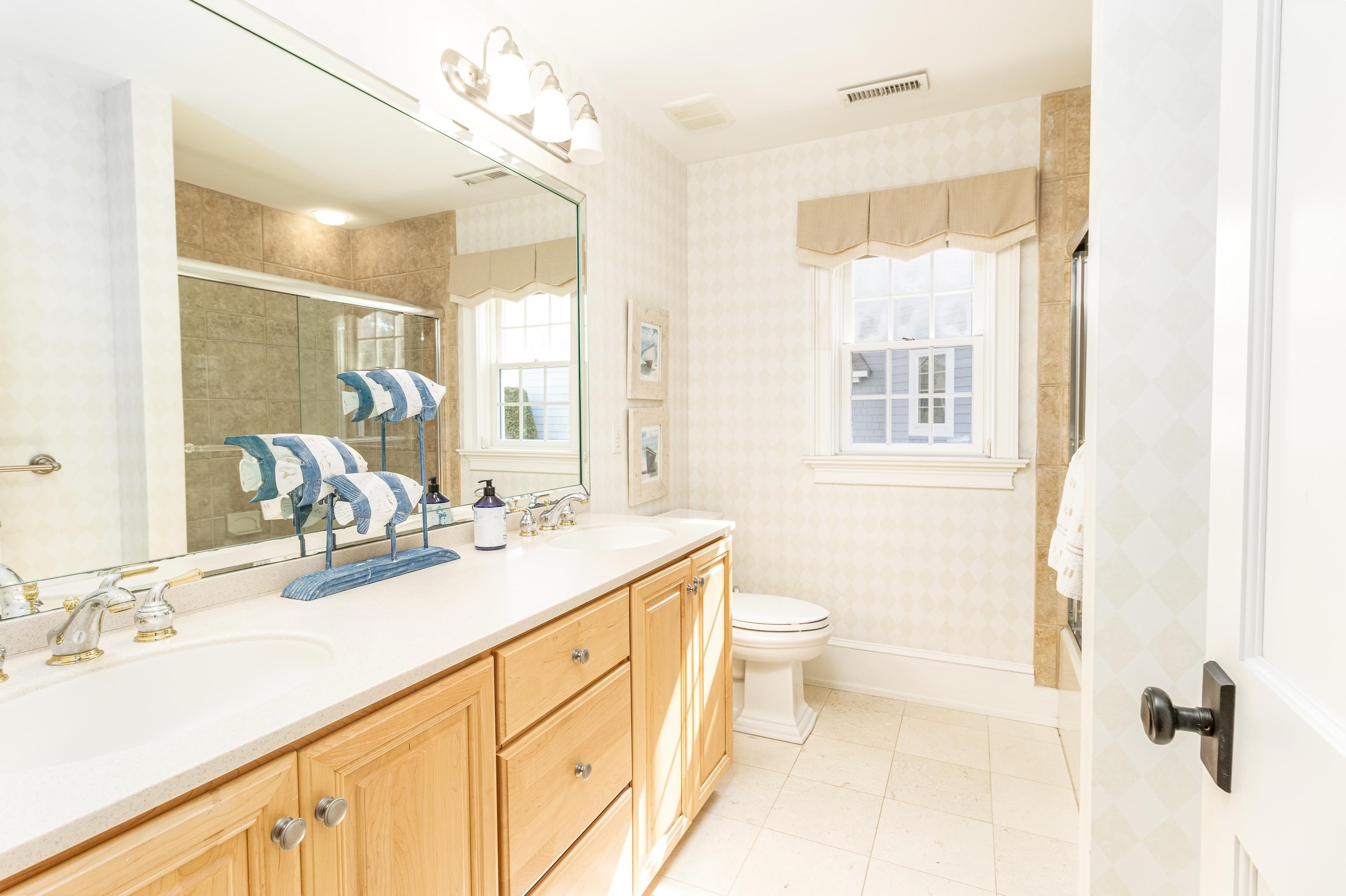 153 76th Street Avalon, NJ 08202 - Photo 15 of 33 a bathroom with a granite countertop sink a toilet a mirror and a shower