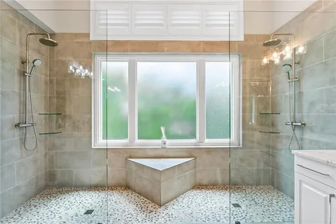 a bathroom with a granite countertop sink mirror and a bathtub next to a window