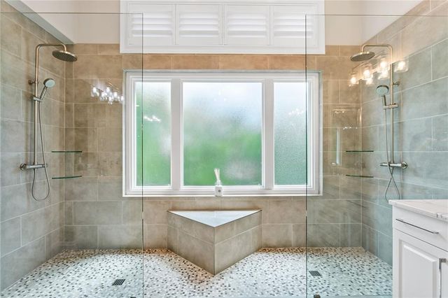 a bathroom with a granite countertop sink mirror and a bathtub next to a window