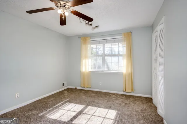 an empty room with closet and a chandelier fan