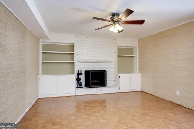 an empty room with chandelier fan and windows