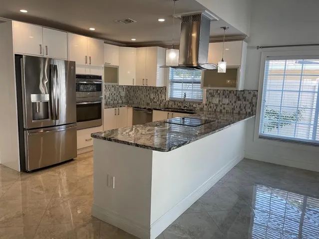 a kitchen with stainless steel appliances granite countertop a refrigerator a stove and a sink