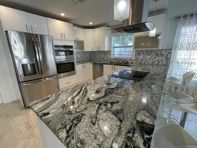 a kitchen with stainless steel appliances granite countertop a sink a stove and a refrigerator