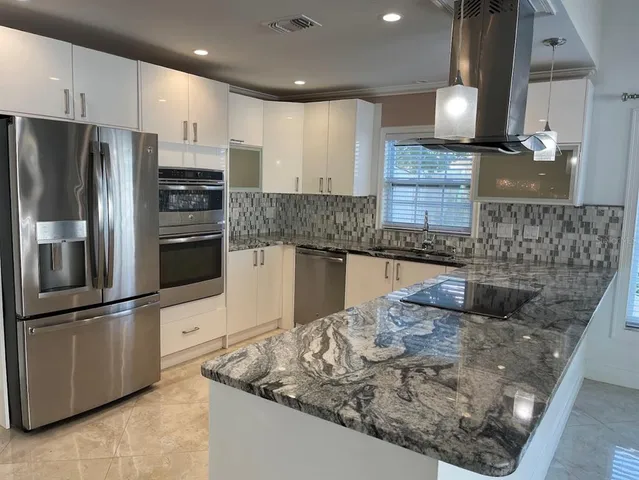 a kitchen with stainless steel appliances granite countertop a sink a stove and a refrigerator