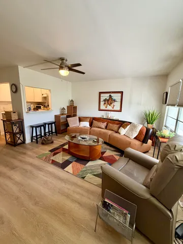 a living room with furniture kitchen view and a large window