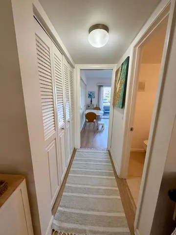 a view of a hallway to a livingroom with wooden floor and staircase