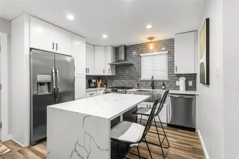 a kitchen with a refrigerator a sink a stove a dining table and chairs