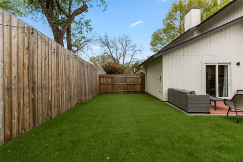 a view of backyard with wooden fence and a large tree