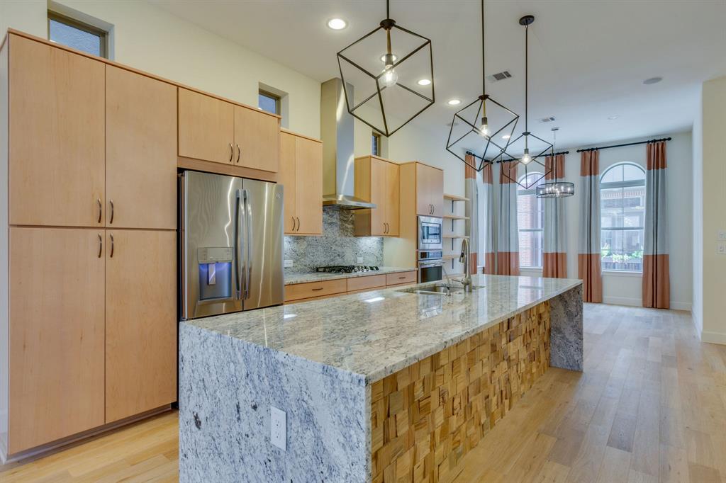a kitchen with stainless steel appliances granite countertop a refrigerator a sink and a chandelier