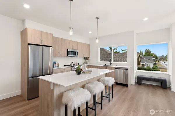 a kitchen with stainless steel appliances granite countertop a refrigerator a sink a dining table and chairs