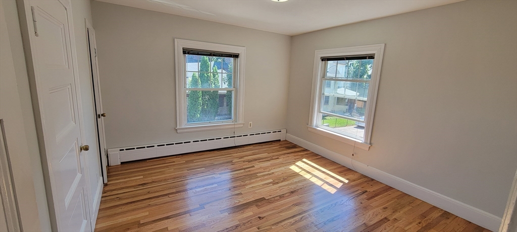 88 Corey Street, Unit 2 Boston, MA 02132 - Photo 11 of 23 a view of an empty room with wooden floor and a window