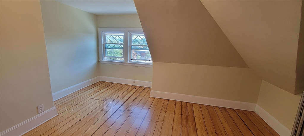 88 Corey Street, Unit 2 Boston, MA 02132 - Photo 21 of 23 a view of an empty room with wooden floor and a window