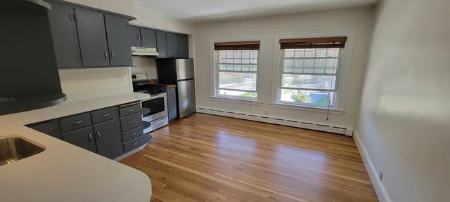 a view of empty room with wooden floor and a window