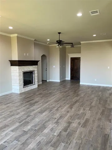 an empty room with wooden floor fireplace and windows