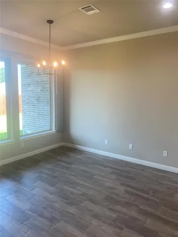 a view of an empty room with wooden floor and windows