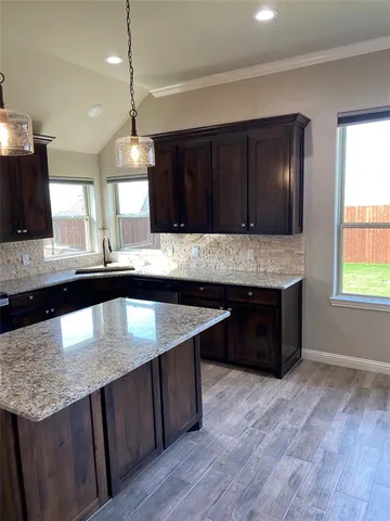 a kitchen with kitchen island stainless steel appliances a sink stove and wooden floor