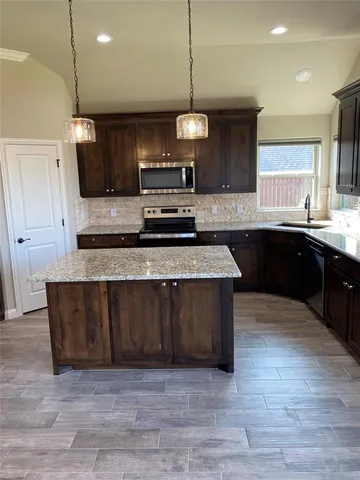 a large kitchen with stainless steel appliances granite countertop a stove a sink and a microwave