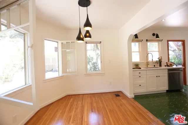 a view of an empty room with window and wooden floor