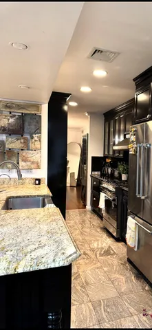 a kitchen with stainless steel appliances kitchen island granite countertop a refrigerator and stove