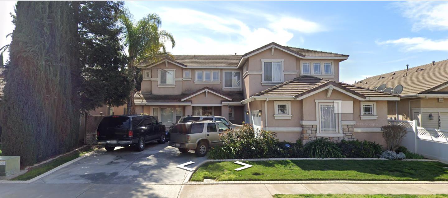 a view of a white house next to a yard with plants and trees