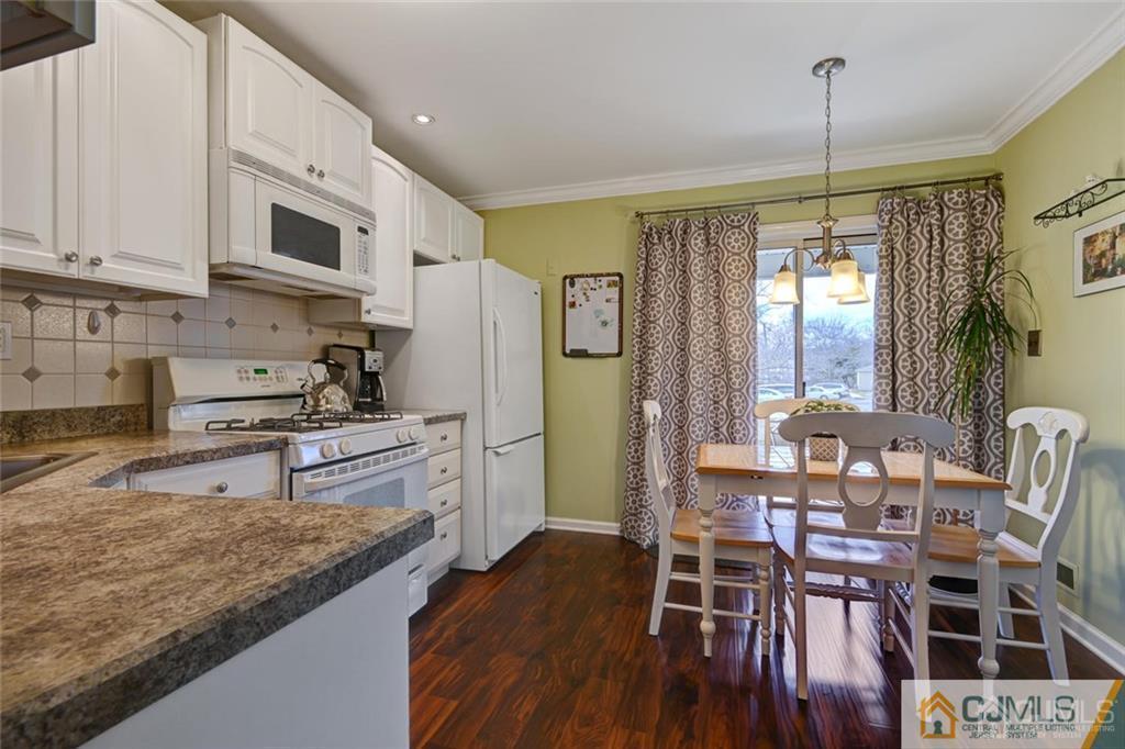 360 Constitution Circle North Brunswick, NJ 08902 - Photo 5 of 21 a kitchen with stainless steel appliances granite countertop a stove top oven a refrigerator a dining table and chairs with wooden floor