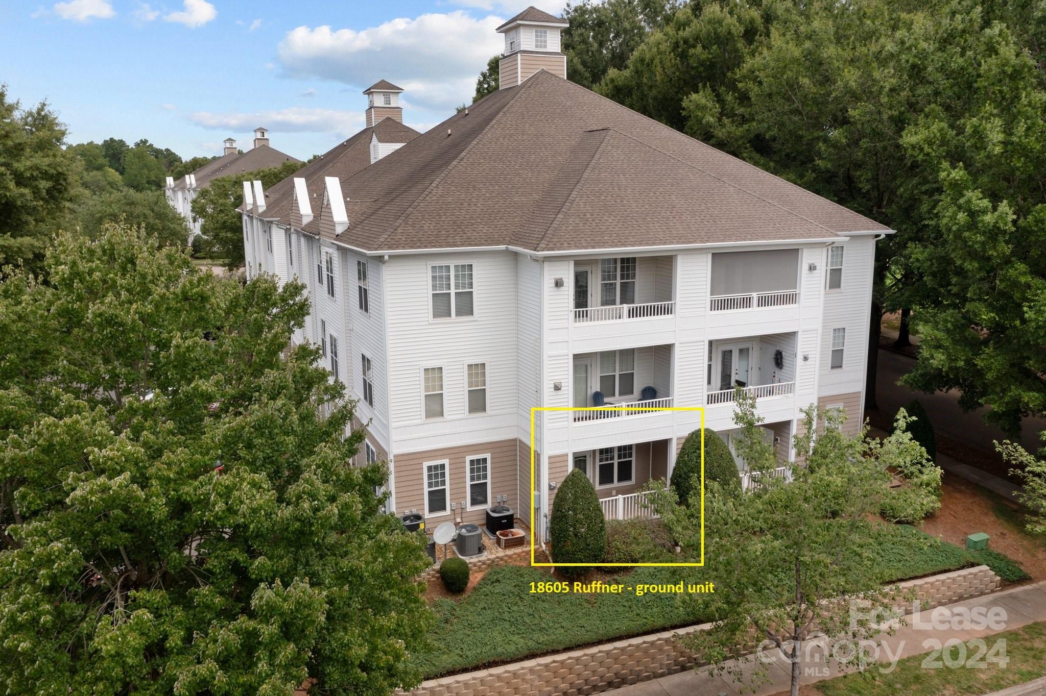 a view of a white house next to a yard with big trees