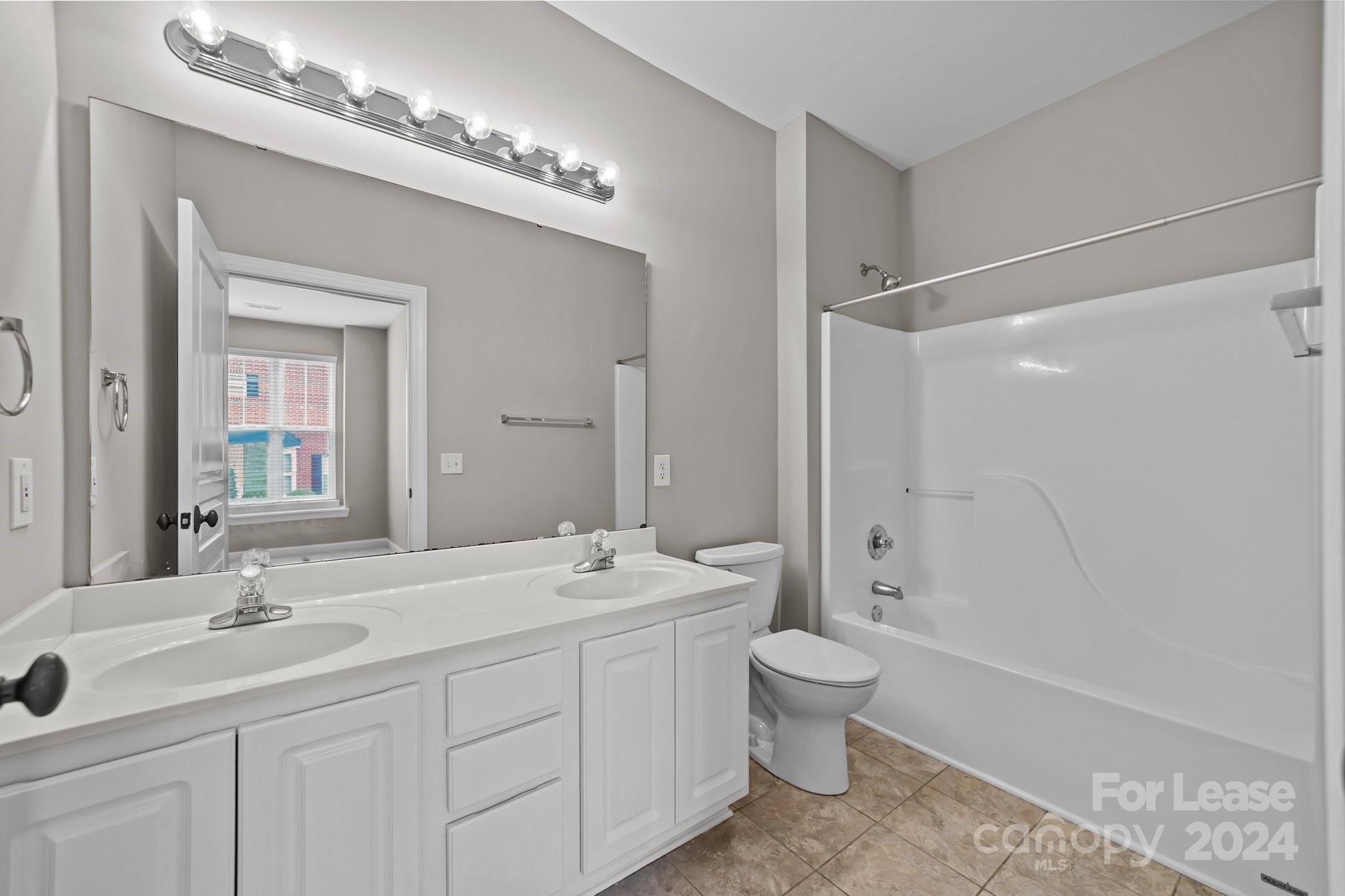 18605 Ruffner Drive, Unit 1C Cornelius, NC 28031 - Photo 15 of 27 a bathroom with a double vanity sink toilet mirror and bathtub