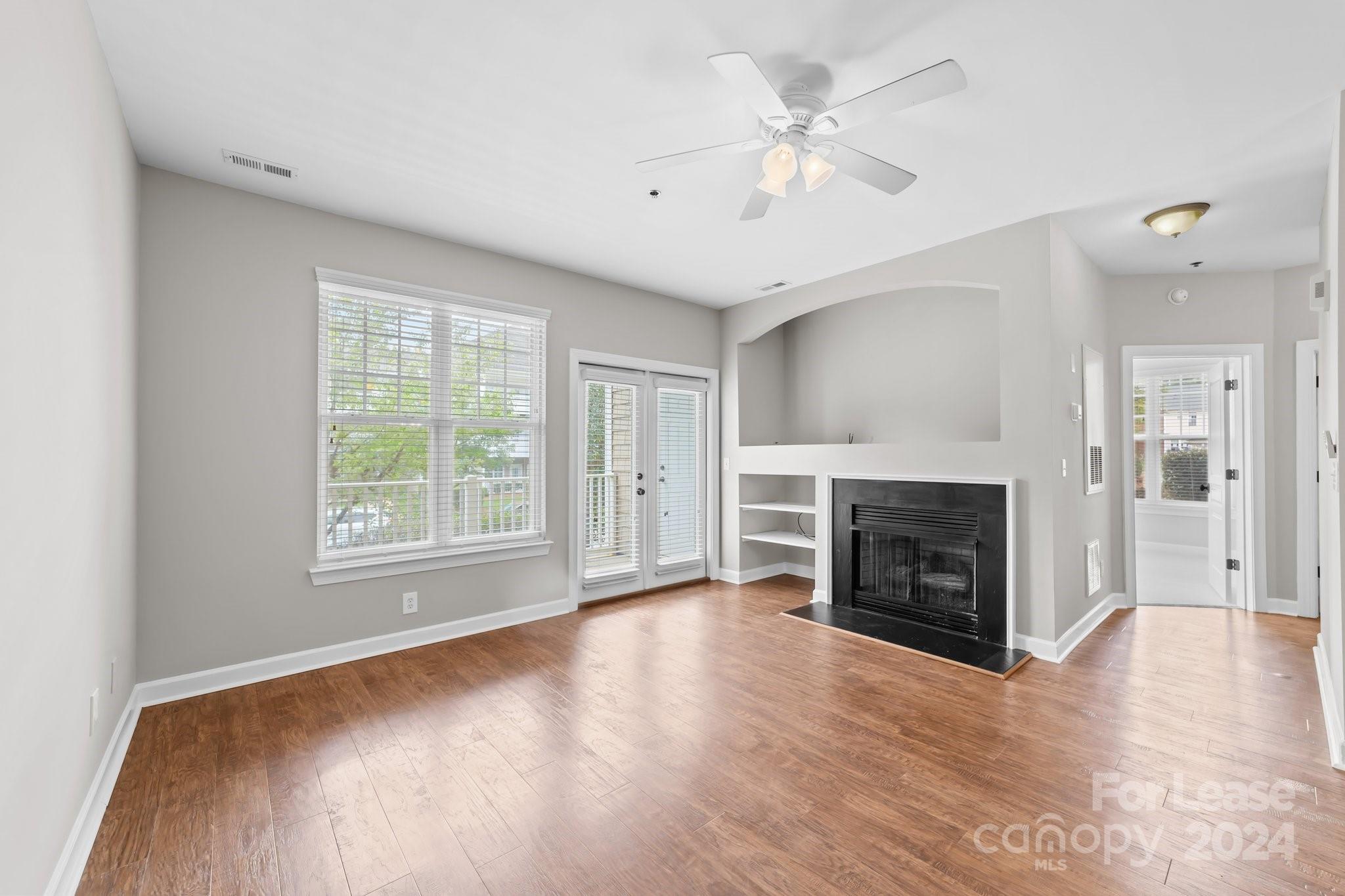 18605 Ruffner Drive, Unit 1C Cornelius, NC 28031 - Photo 5 of 27 an empty room with windows a fireplace and wooden floor