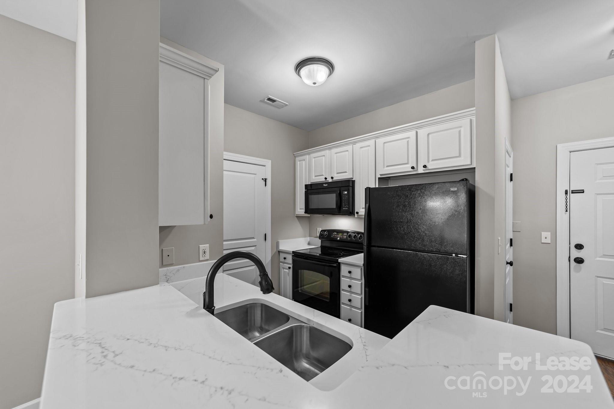 18605 Ruffner Drive, Unit 1C Cornelius, NC 28031 - Photo 8 of 27 a kitchen with stainless steel appliances kitchen island a refrigerator sink and cabinets