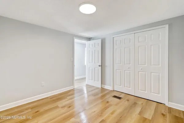an empty room with wooden floor cabinet and windows