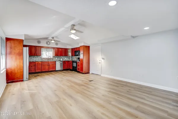 a kitchen with stainless steel appliances granite countertop a refrigerator a sink dishwasher a stove with wooden cabinets and floor
