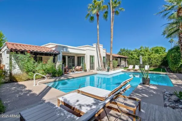 a view of a house with backyard swimming pool and sitting area