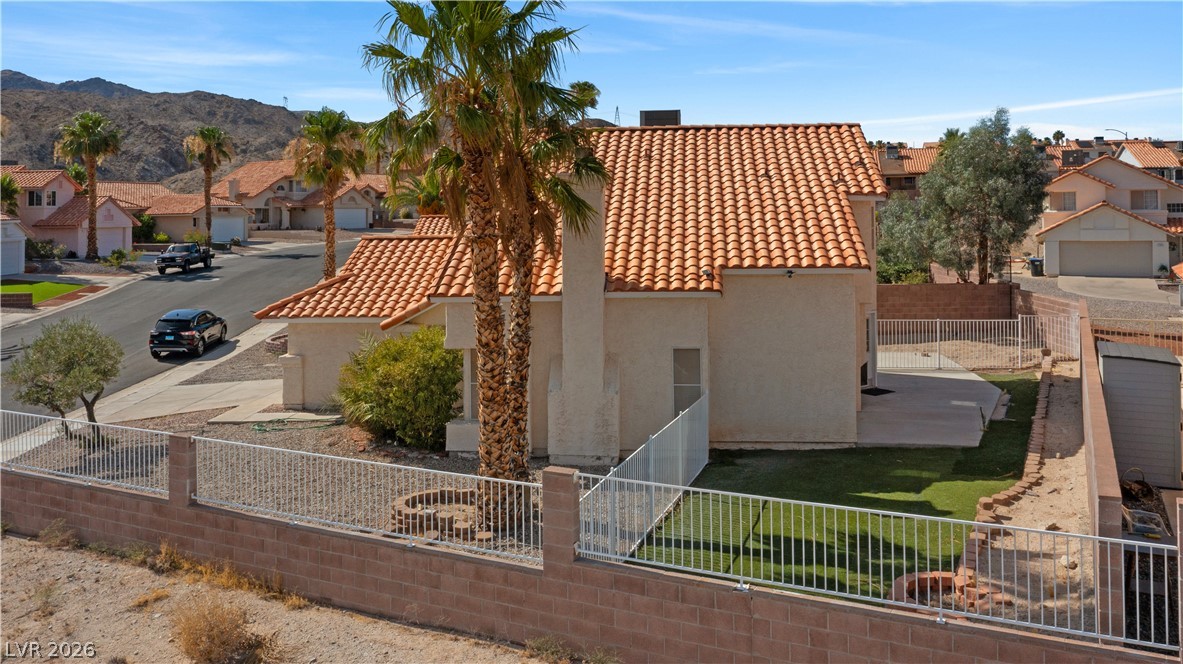 3156 Terrace View Drive Laughlin, NV 89029 - Photo 81 of 94 An inviting neighborhood unfolds with terracotta-tiled roofs, mature palm trees, and mountain vistas under a bright sky.