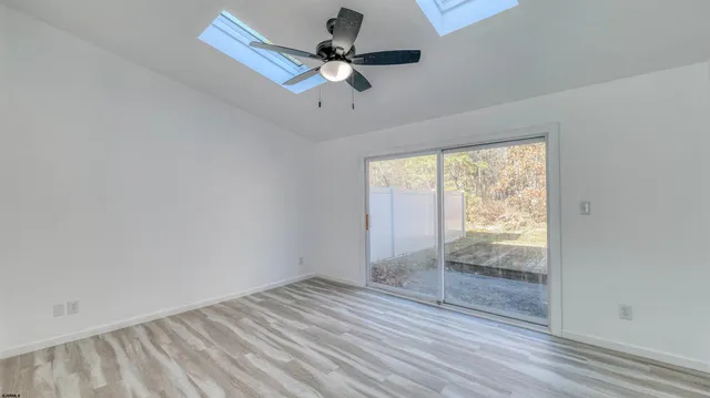 a view of empty room with wooden floor and ceiling fan