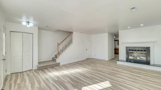 a view of an empty room with wooden floor fireplace and a window