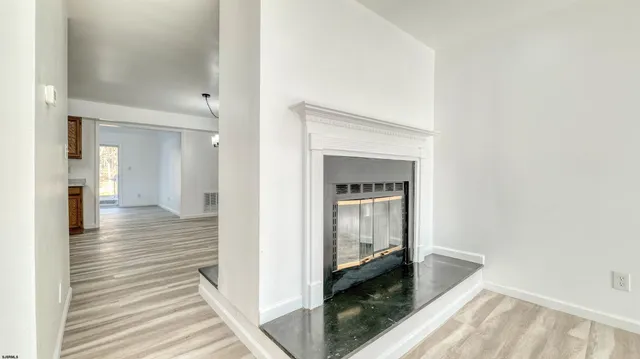 a hallway with wooden floor fireplace and living room