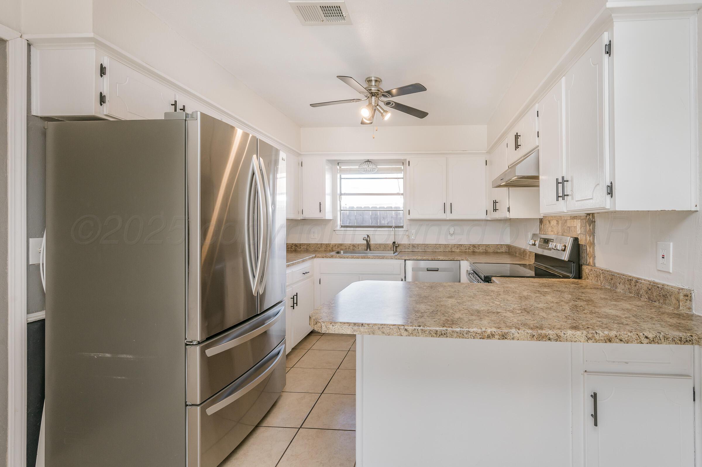 5336 Wheeler Lane Amarillo, TX 79110 - Photo 7 of 24 a kitchen with granite countertop a refrigerator a sink a stove and white cabinets