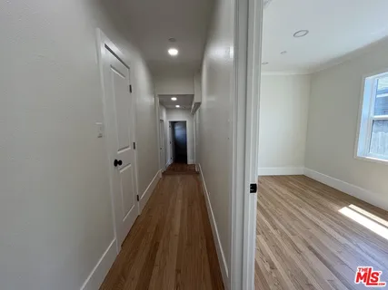 a view of empty room with wooden floor and fan