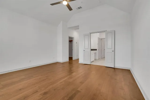 an empty room with wooden floor cabinet and windows