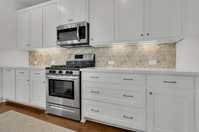 a kitchen with white cabinets and stainless steel appliances