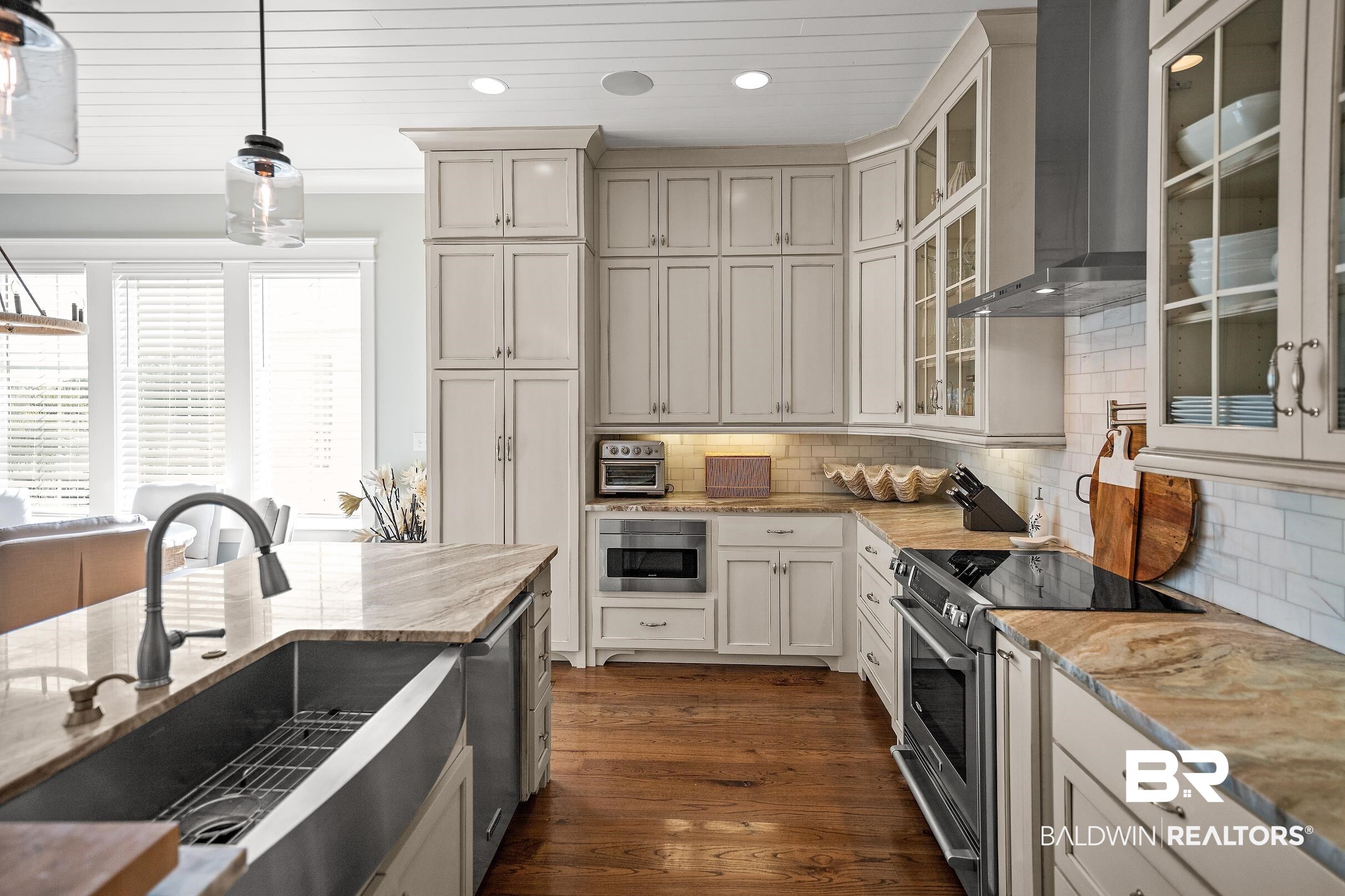 33186 Marlin Key Drive Orange Beach, AL 36561 - Photo 37 of 87 Dual tone kitchen with stainless steel appliances, light stone counters, decorative light fixtures, dark wood-style flooring, and glass fronted cabinets