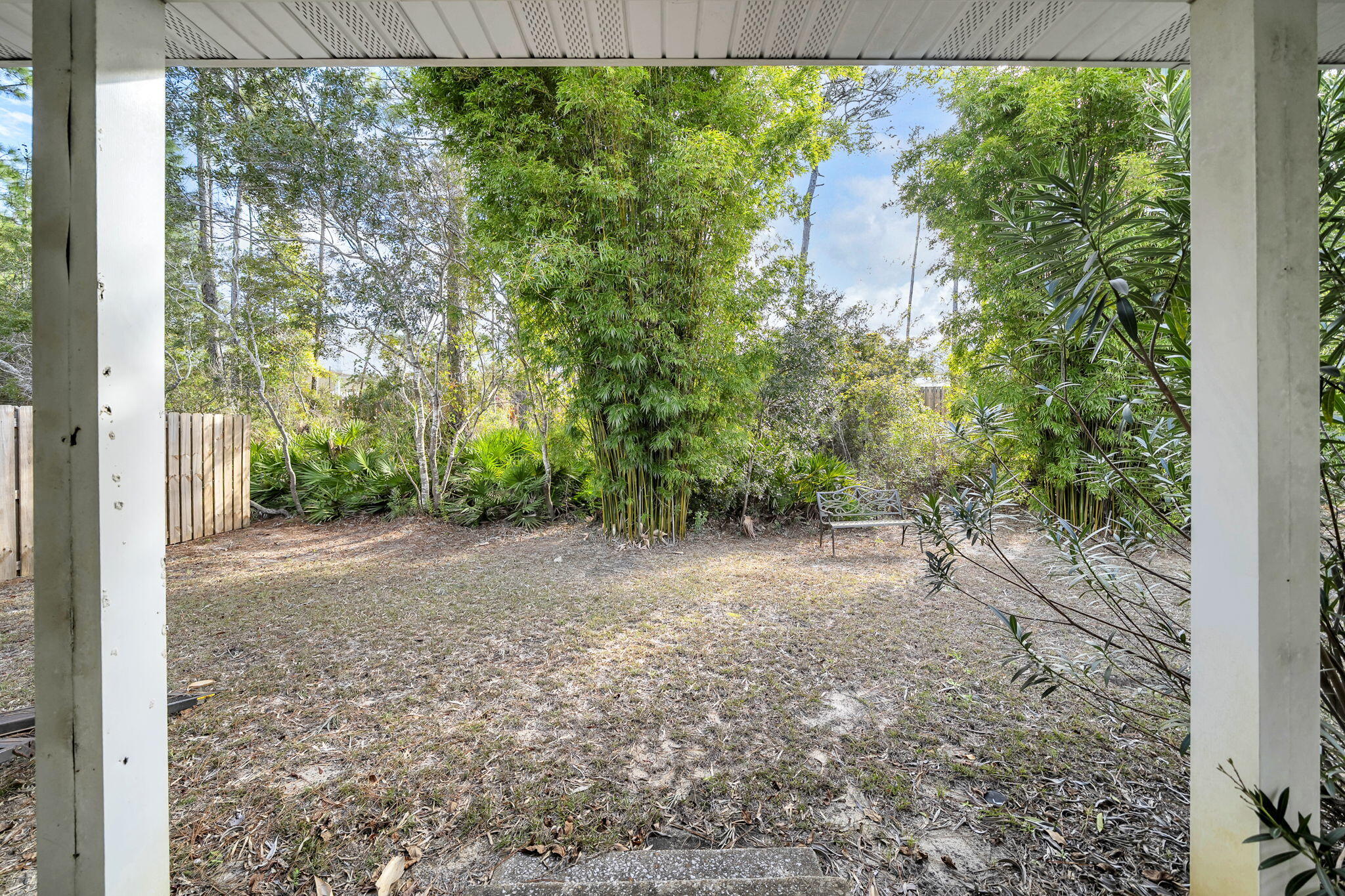 386 Hunters Road Santa Rosa Beach, FL 32459 - Photo 30 of 35 a view of a yard with plants and a bench under an umbrella