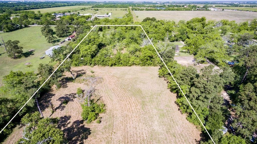 6716 Sjolander Road Baytown, TX 77521 - Photo 4 of 26 A large, rectangular plot of land, partially cleared with a mix of open fields and wooded areas, offering a blend of natural privacy and space for development. The property is outlined, indicating the boundaries of the lot.