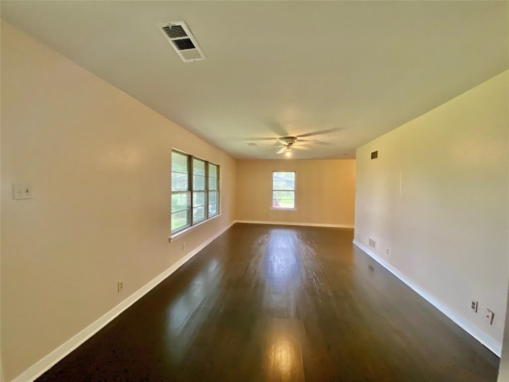 6716 Sjolander Road Baytown, TX 77521 - Photo 7 of 26 Spacious, well-lit room with gleaming hardwood floors, neutral wall colors, and a ceiling fan. There are multiple windows allowing for plenty of natural light.