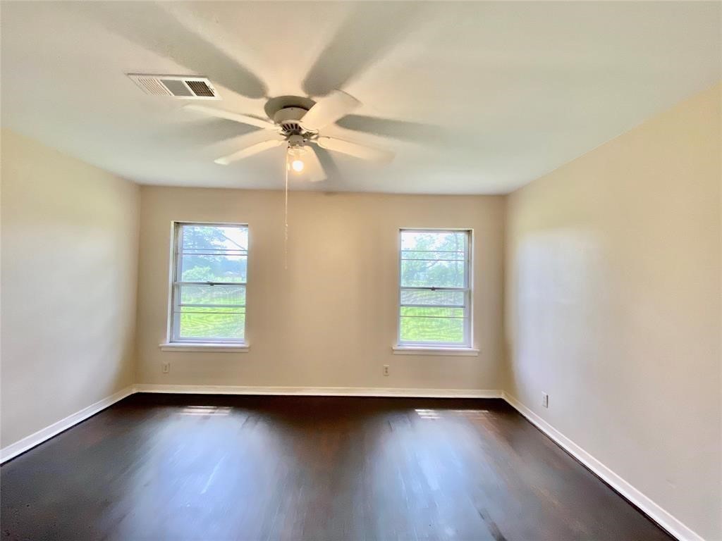 6716 Sjolander Road Baytown, TX 77521 - Photo 8 of 26 Bright dining room featuring glossy dark wood floors, a neutral wall color, two windows providing natural light, and a ceiling fan with lighting.