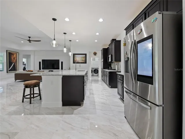 a kitchen with stainless steel appliances kitchen island granite countertop a refrigerator a stove top oven and a sink with cabinets