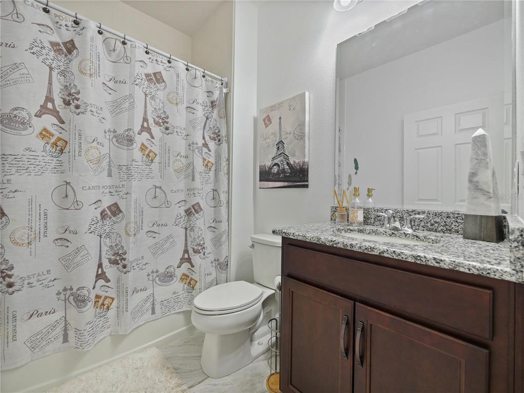 5264 Obsidian Gate Road Mount Dora, FL 32757 - Photo 23 of 49 a bathroom with a granite countertop toilet sink and mirror