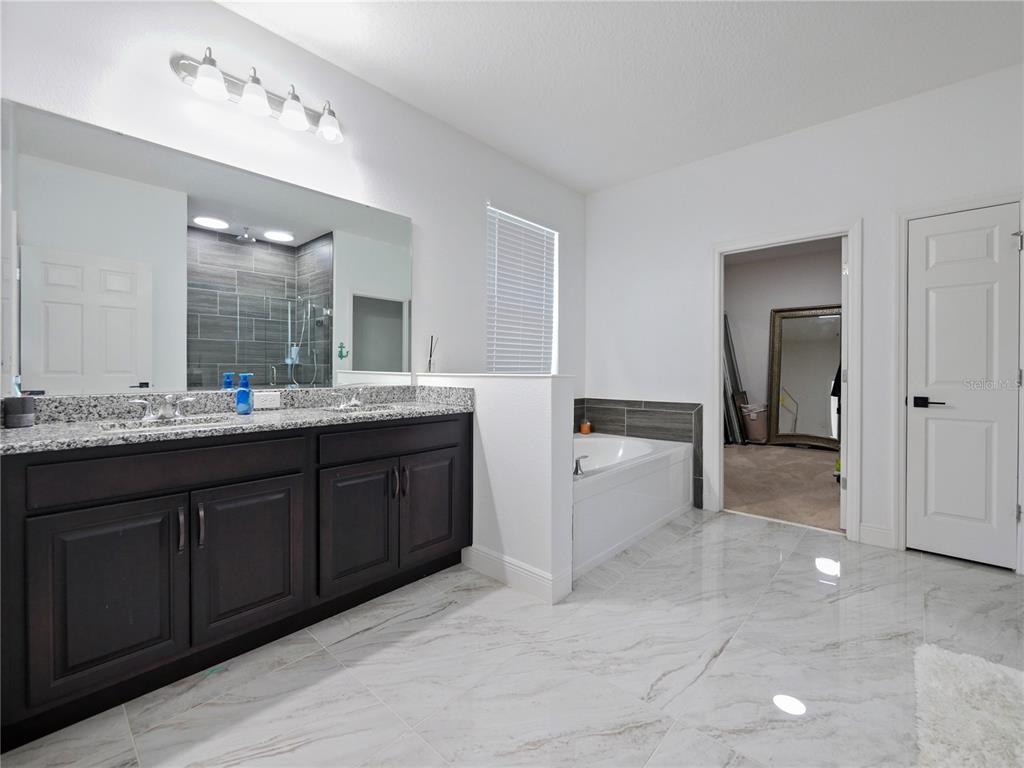 5264 Obsidian Gate Road Mount Dora, FL 32757 - Photo 30 of 49 a spacious bathroom with a granite countertop sink a mirror and a vanity