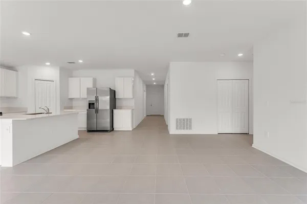 a view of kitchen with refrigerator and white cabinets