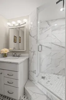 a bathroom with a granite countertop sink a mirror and shower